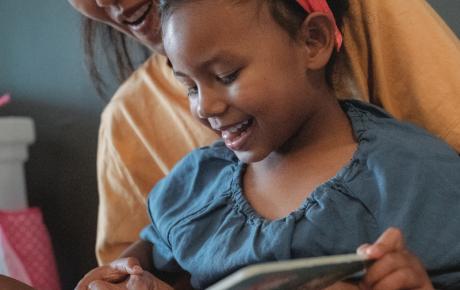 picture of a little girl and a mother reading together from a book, smiling